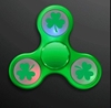 Green fidget spinner with lights of green, red and blue including printed images of shamrocks. 